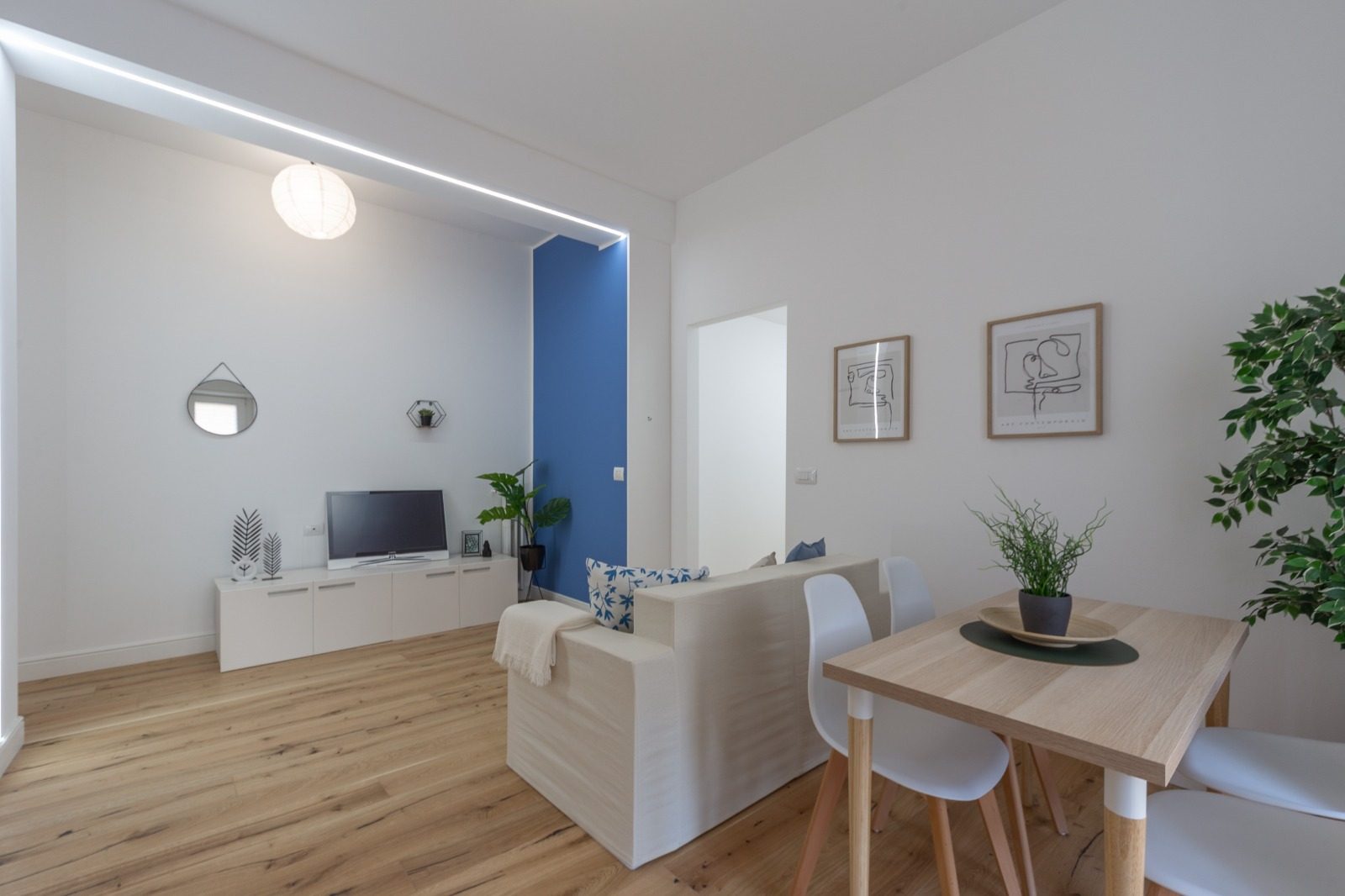 Zona giorno con parete blu, TV a muro e parquet in rovere a doghe larghe
