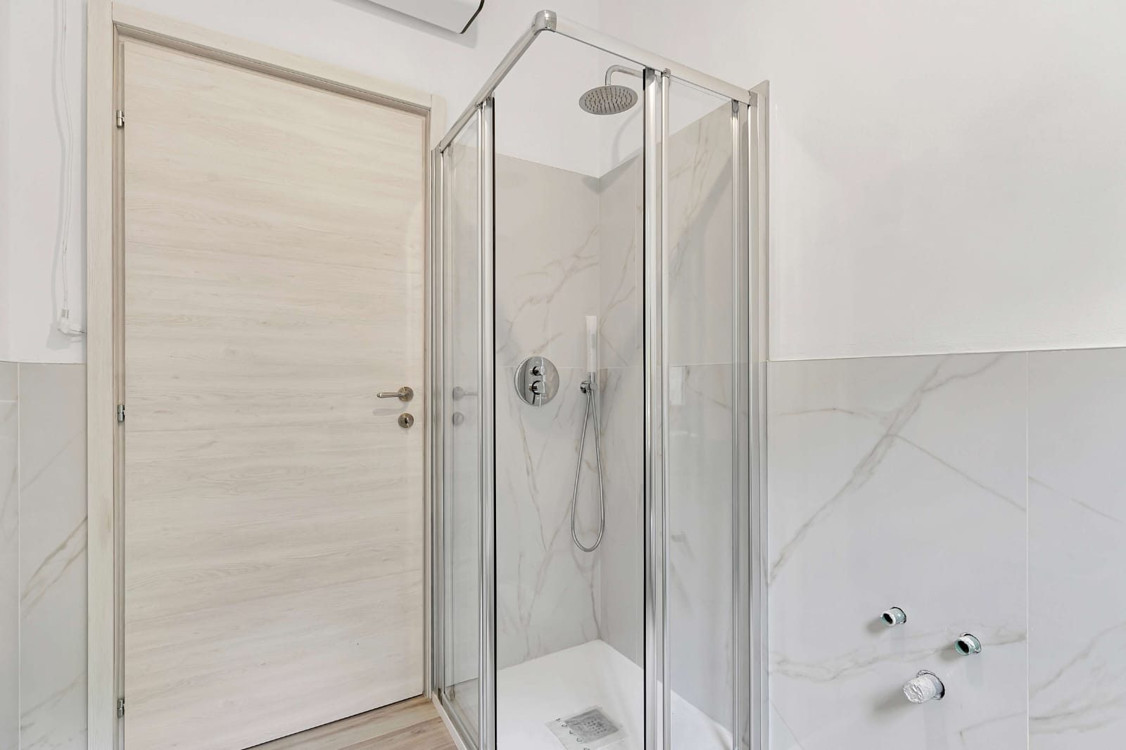 Bagno con box doccia in cristallo e rivestimento in gres effetto marmo