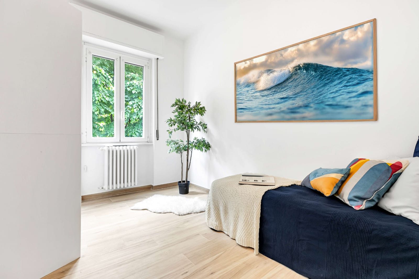 Camera da letto con pavimento in legno chiaro, pareti bianche e letto con copriletto blu