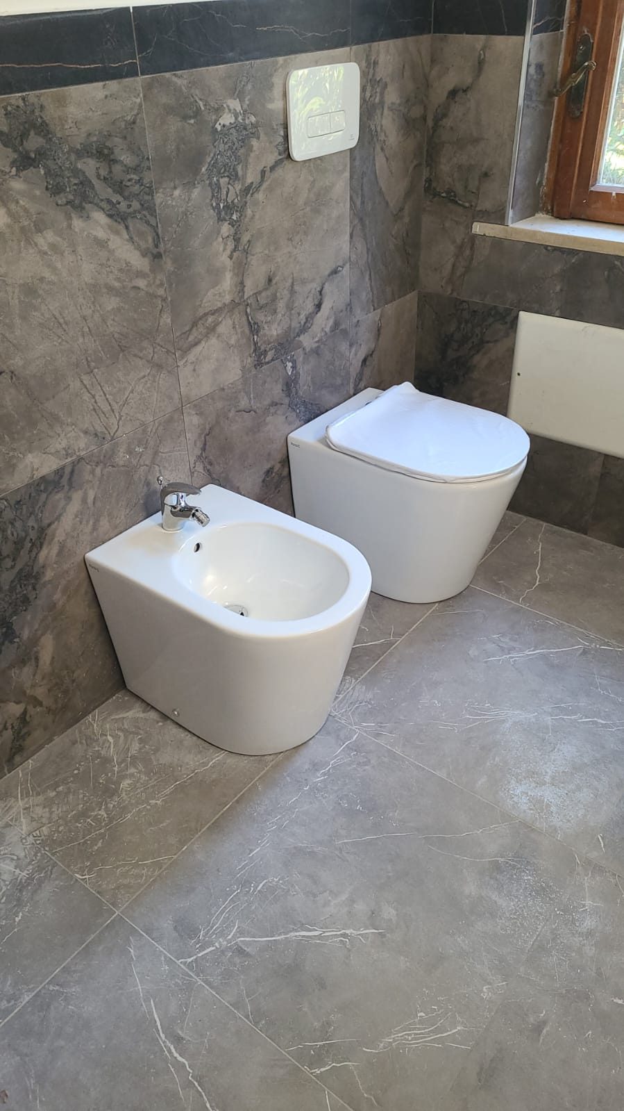 Bagno con rivestimento in gres effetto marmo grigio e sanitari sospesi