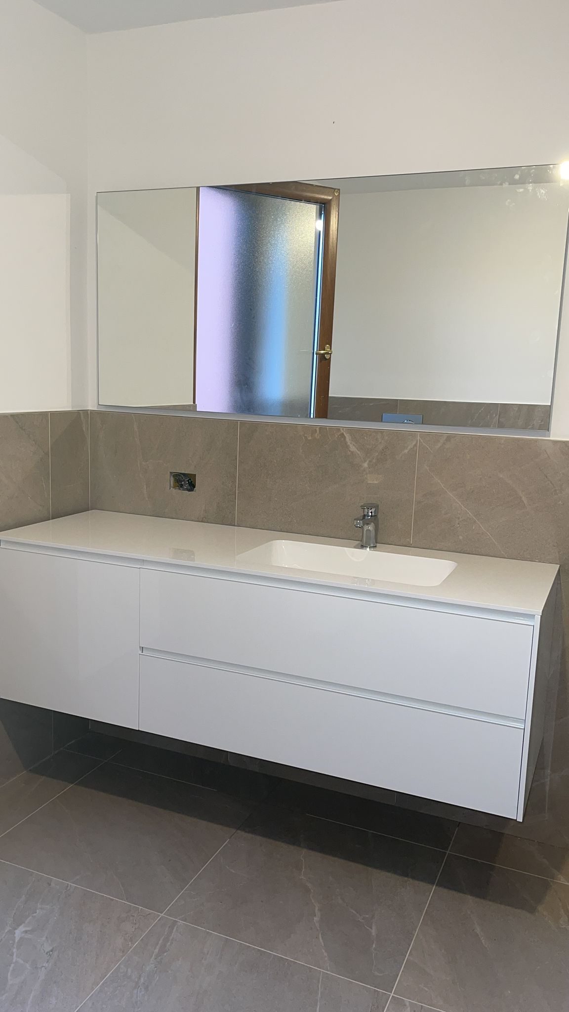 Mobile bagno sospeso bianco con lavabo integrato, specchio a parete e rivestimento in gres beige