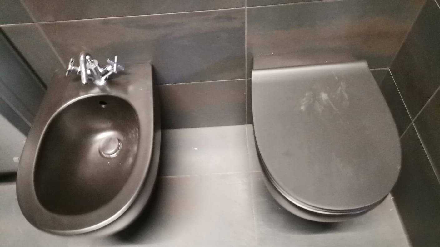 Bidet e vaso sospesi color antracite affiancati, pareti e pavimento in gres grigio