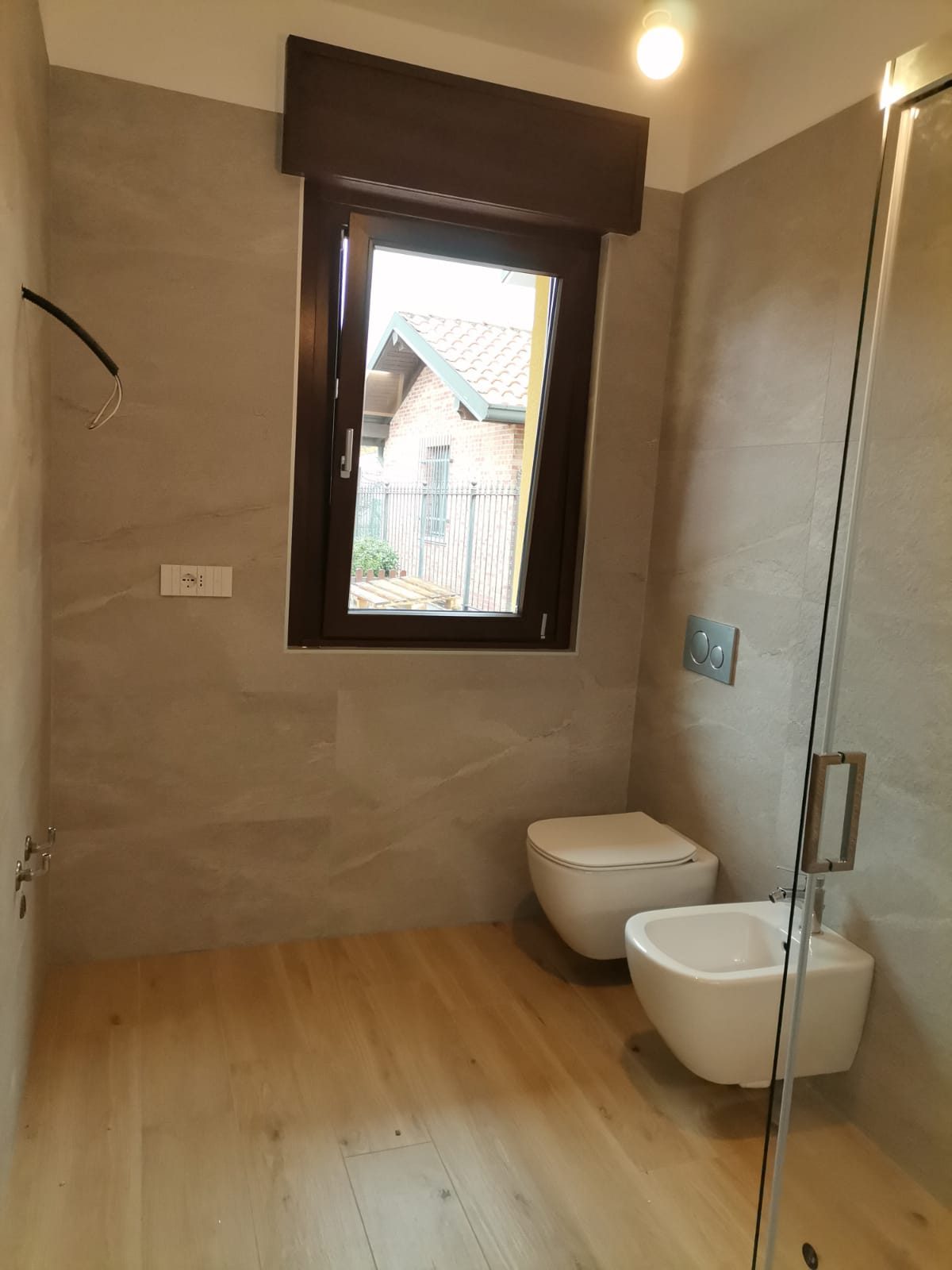 Bagno finito con rivestimento in gres effetto pietra e sanitari sospesi