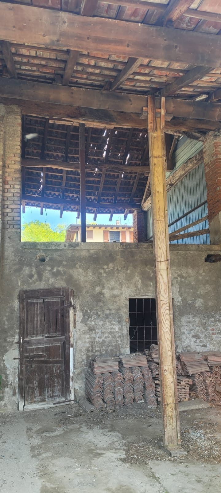 Interno del fabbricato con orditura del tetto in legno puntellata e coppi accatastati per il reimpiego