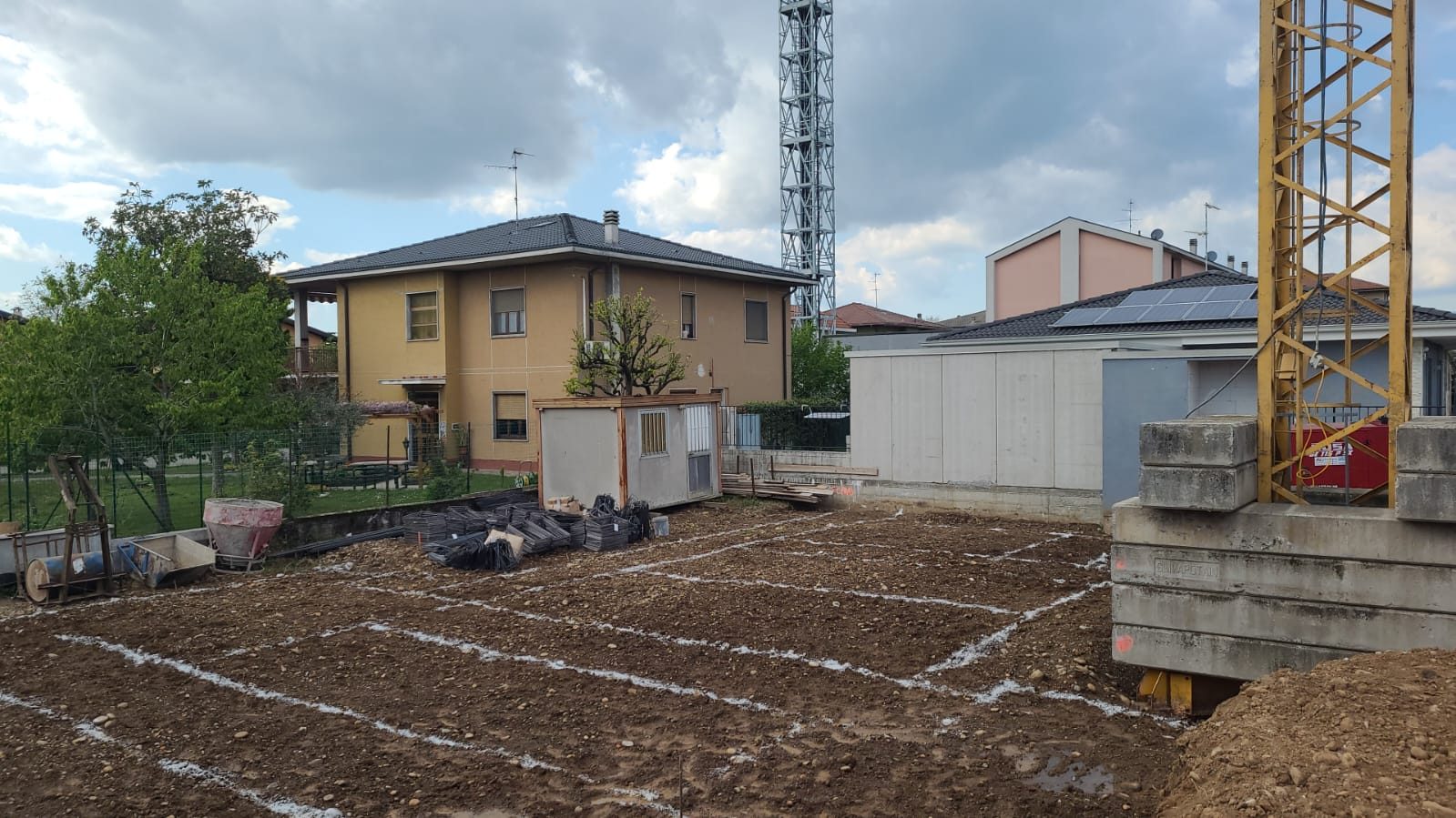 Area di cantiere con tracciamento a calce delle fondazioni, gru a torre e ferri d'armatura