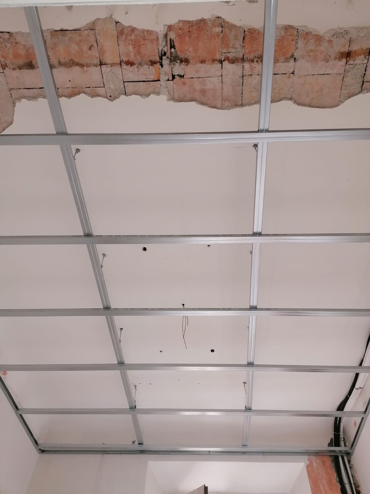 Orditura metallica per controsoffitto in cartongesso fissata al solaio, traccia con mattoni a vista