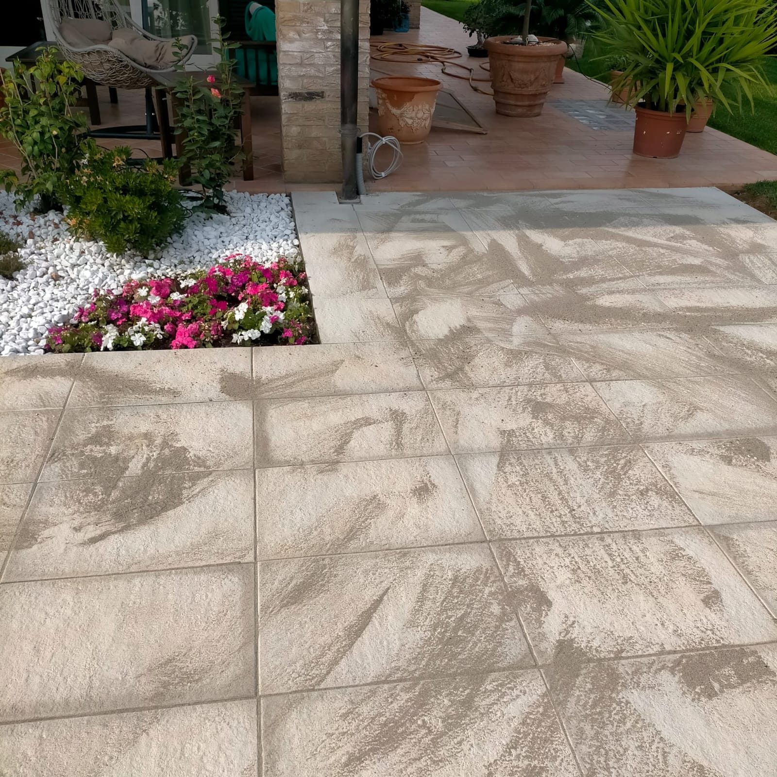 Pavimentazione esterna in lastre effetto pietra posata fino al porticato, con aiuola e ciottoli bianchi