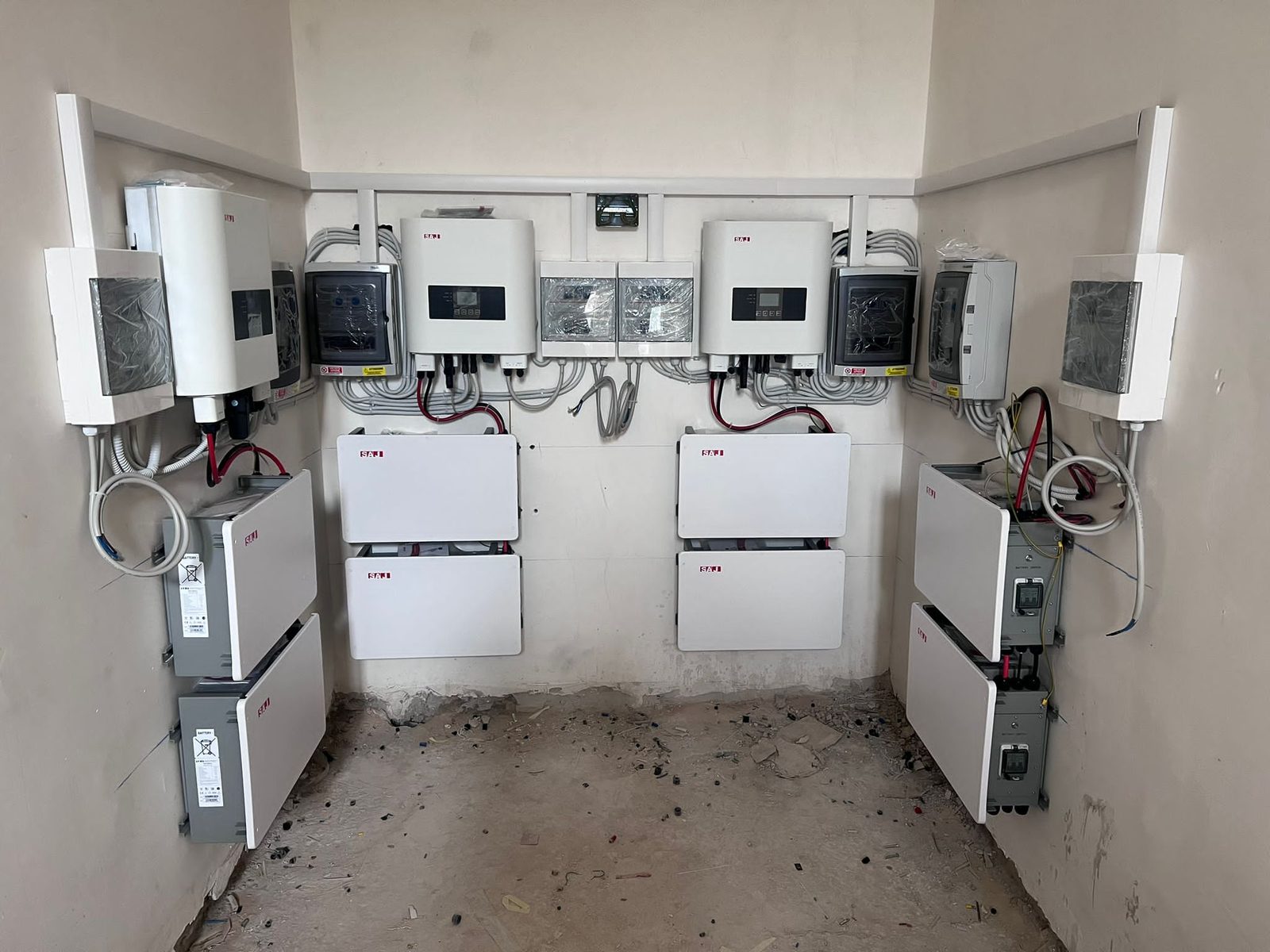 Locale tecnico con inverter a parete, batterie di accumulo impilate e quadri elettrici collegati
