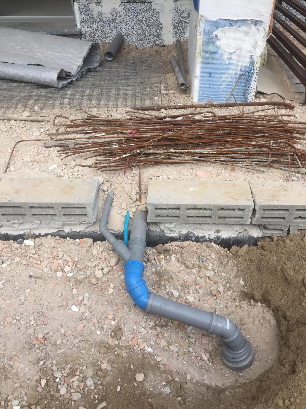 Scavo al piede dell'edificio con tubi di scarico in PVC, cavidotto corrugato e blocchi in calcestruzzo