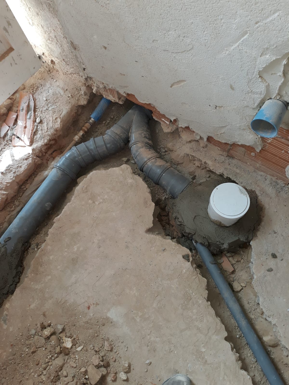 Scarichi in PVC e corrugato blu posati sotto il pavimento, con tappo bianco a protezione