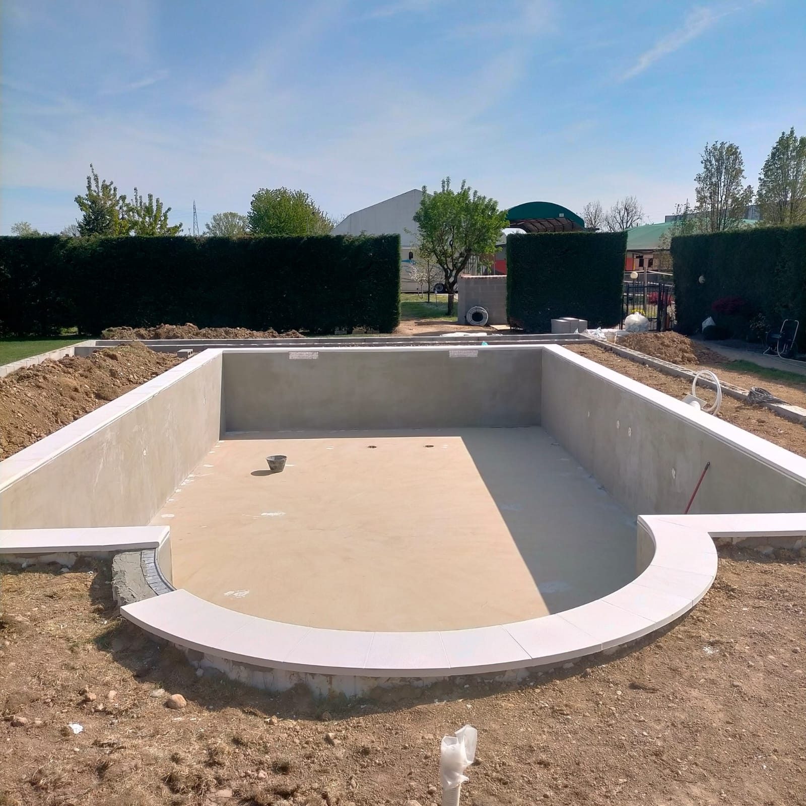 Vasca della piscina interrata in costruzione, con scala e rasatura delle pareti